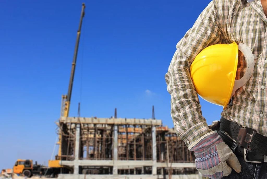 Construction worker holding hard hat at building site
