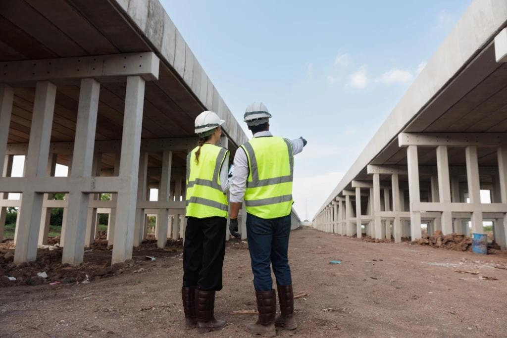 Engineers in hard hats surveying a construction site
